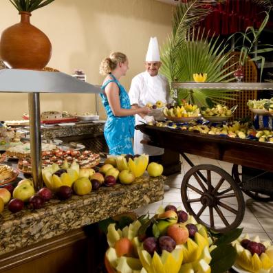 cuisiner et cliente devant chariot de fruits