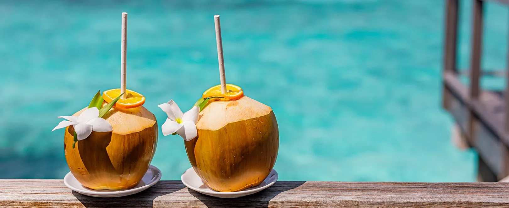 Cocktails noix de coco sur une rambarde au bord de l'eau turquoise