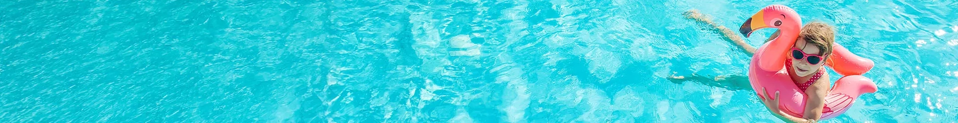 une petite fille dans une bouée rose dans la piscine