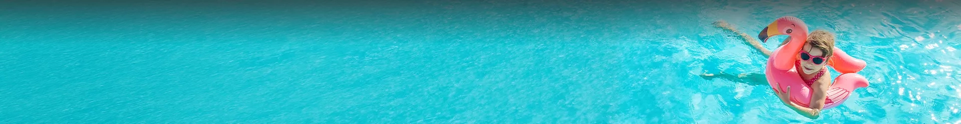 une petite fille dans une bouée rose dans la piscine