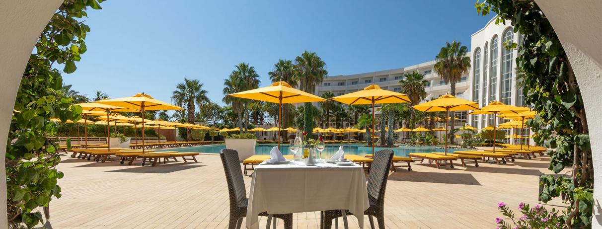 table devant piscine avec parasols jaunes