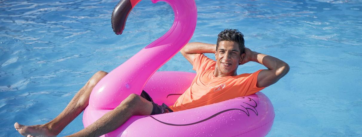 homme allongé dans une bouée flamant rose dans piscine