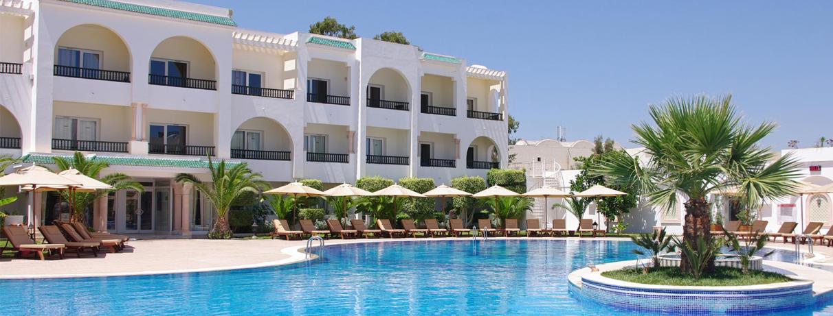 piscine avec palmier au centre et bâtiment hôtel 