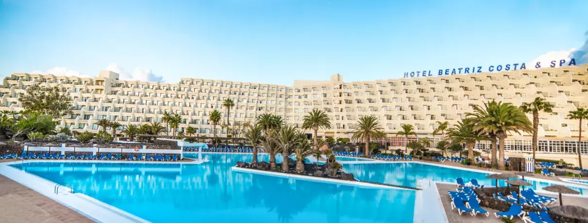 piscine avec palmiers et vue de l'hôtel