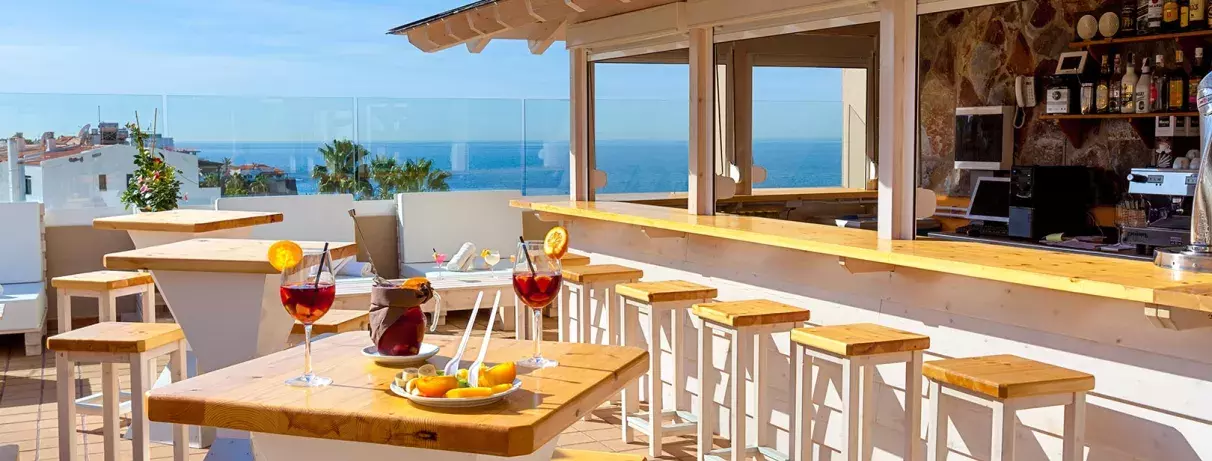 Un bar de terrasse ensoleillé offrant une vue sur l'océan.