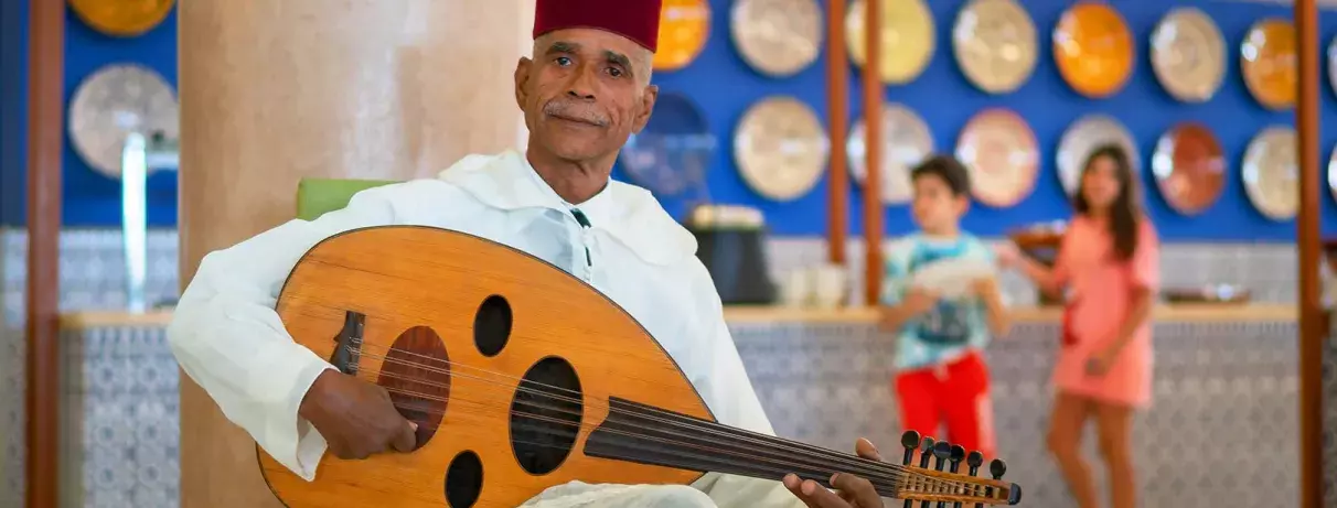musicien tenant un instrument musicale qui est le aoud avec une tenue traditionnelle