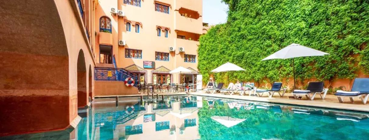 piscine de l'hôtel à l'extérieur donnant sur les terrasse des chambre et au fond des parasols 