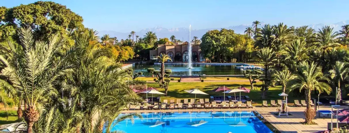 Vue d'ensemble de l'hôtel sur la partie extérieur, piscine, fontaine et jardin avec le bâtiment de l'hôtel
