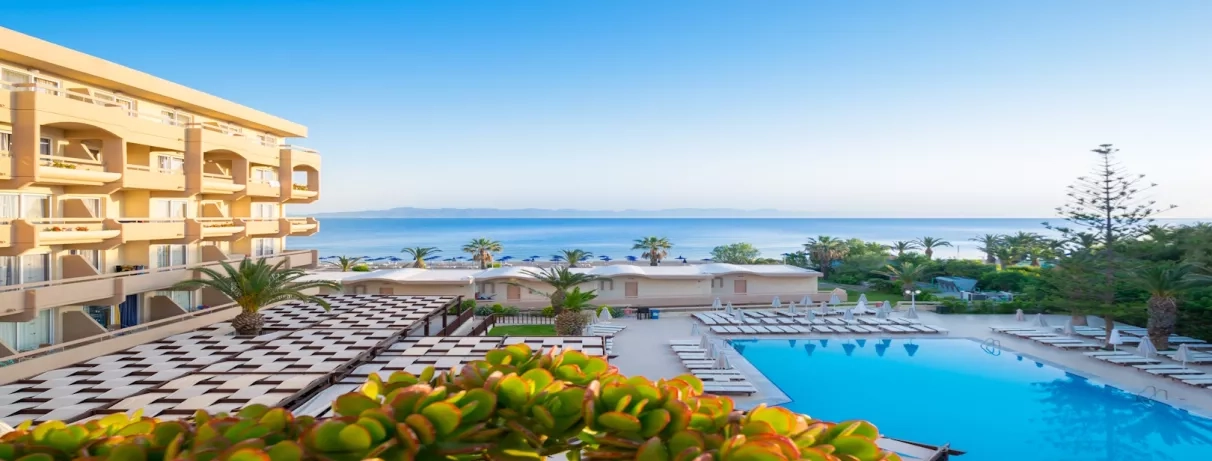 Vue général du haut, bâtiment de l'hôtel, piscine, transats, parasol, plage