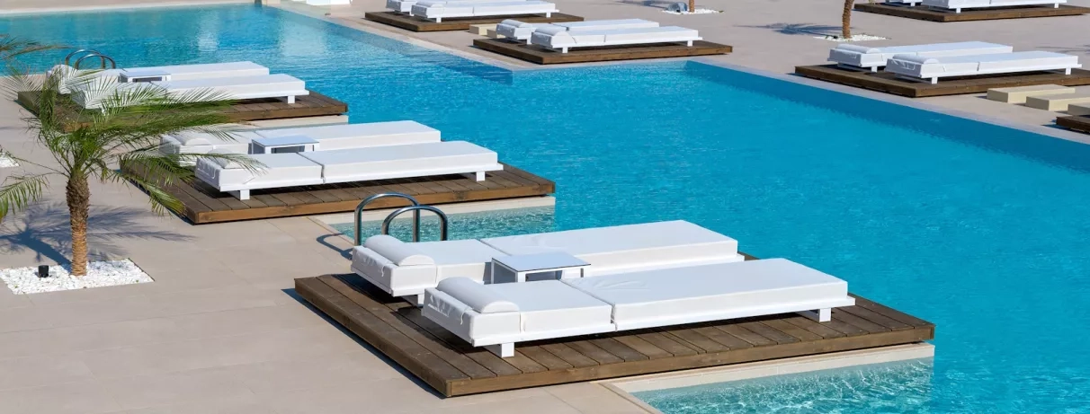 Transats au bord de la piscine palmiers, soleil, relaxation