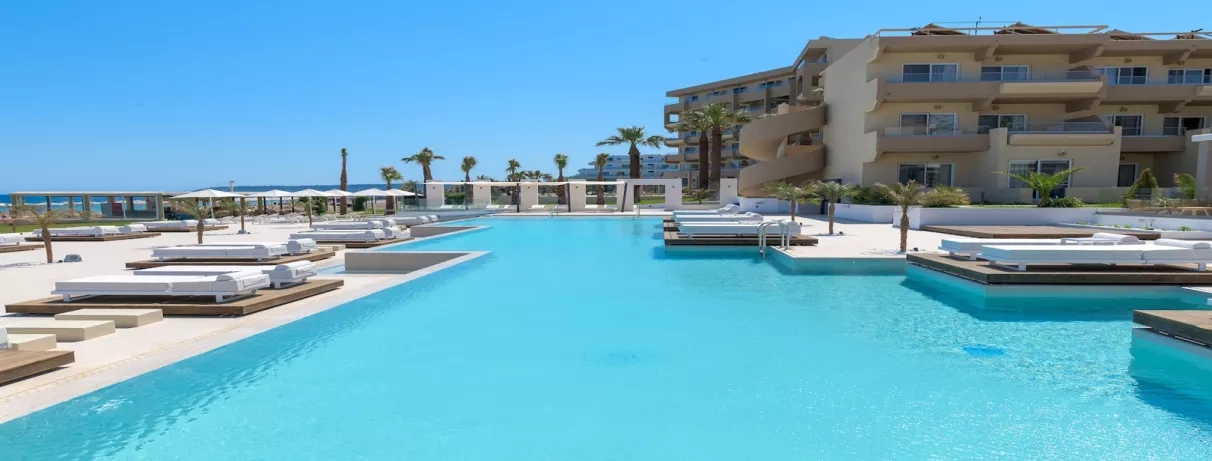 Grande piscine de l'hôtel, bâtiment, transats, parasol, ciel bleu