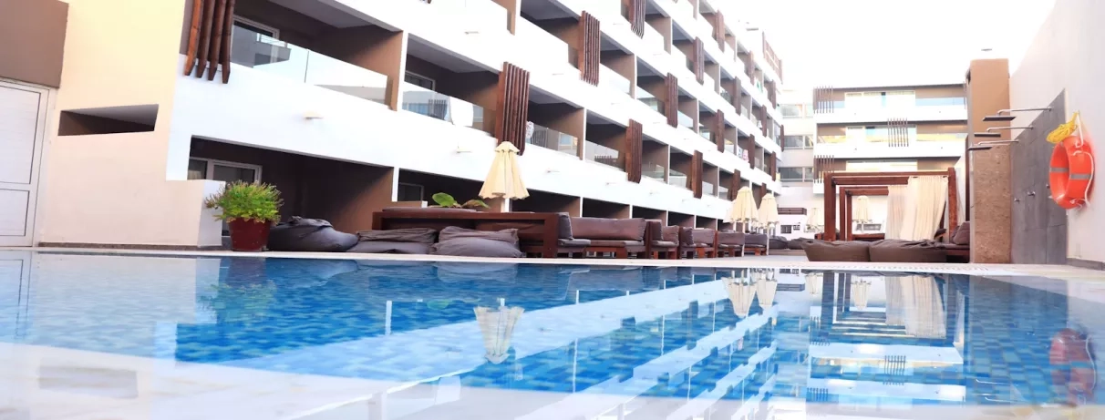 Vue piscine bâtiment de l'hôtel, terrasse, transats