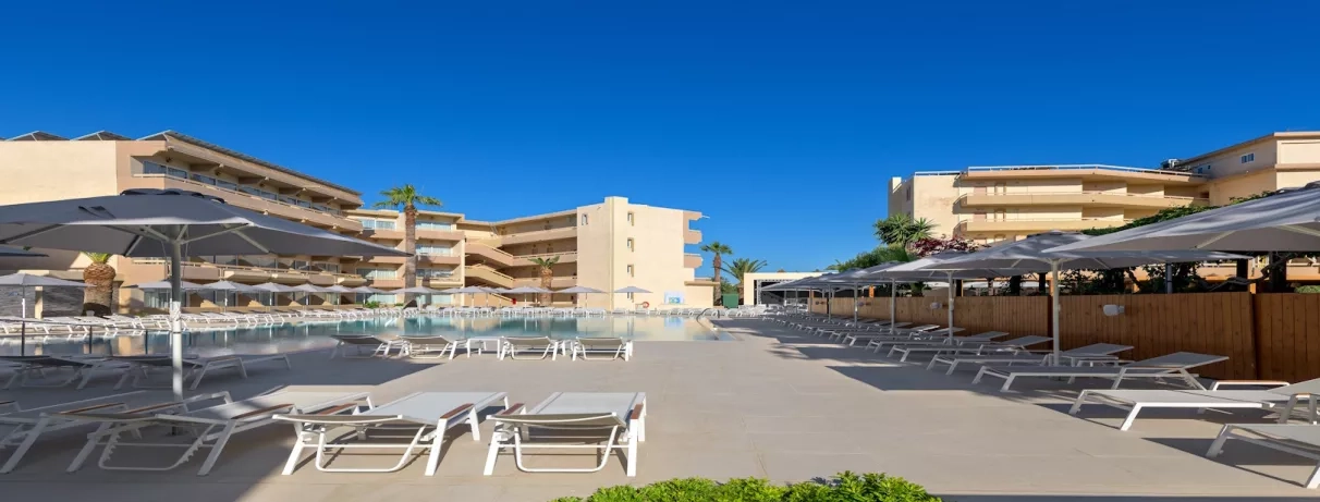 Partie extérieur, bâtiment de l'hôtel, piscine transats et parasol, ciel bleu