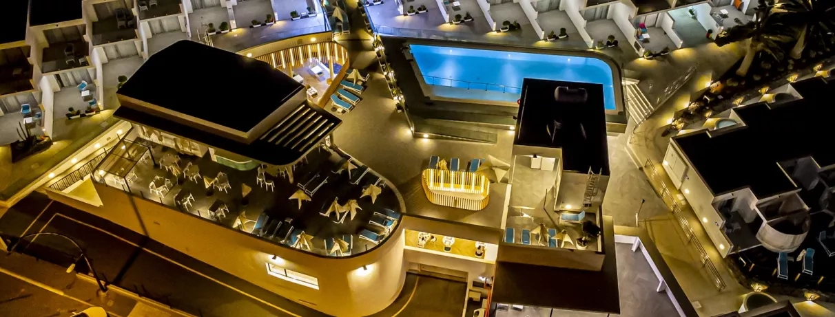 Une vue aérienne nocturne montre les installations de l'hôtel illuminées.