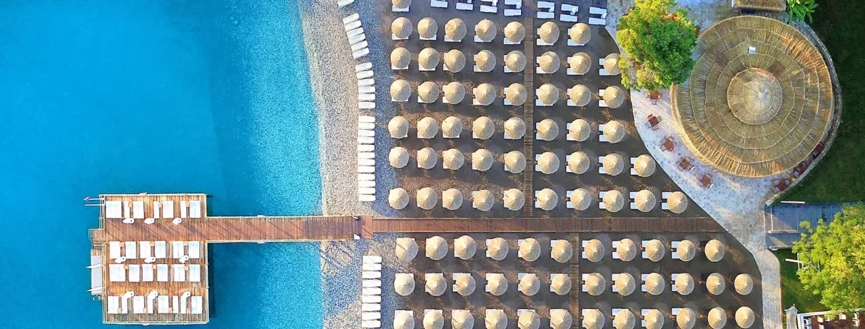 Vue aérienne de l'hôtel et des transats et parasols alignées sur la plage.