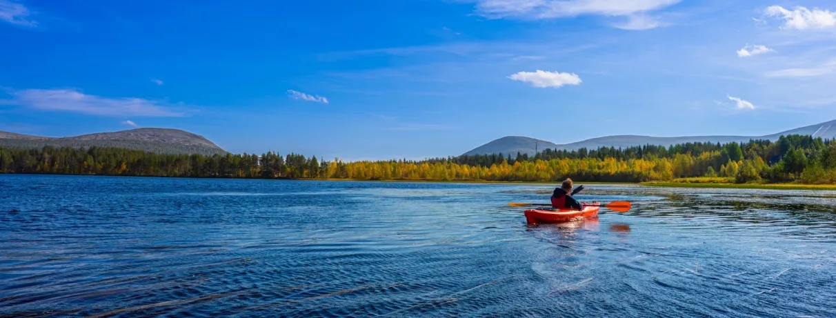 jeune homme faisant du canoe sur un lac de laponie finlandaise lors d'un séjour à l'hôtel levi spa