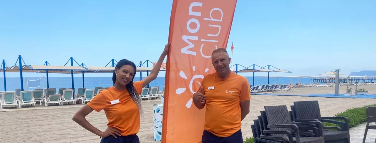 Deux animateurs mondi club sourient sur une terrasse en bord de mer.