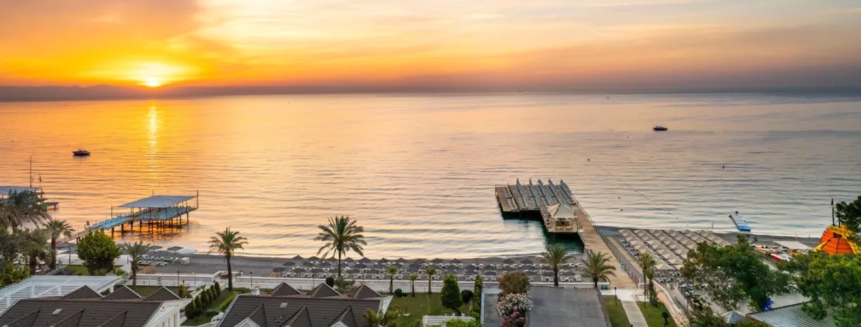 Vue d’un coucher de soleil sur l’horizon, avec des teintes chaudes se reflétant sur la mer.