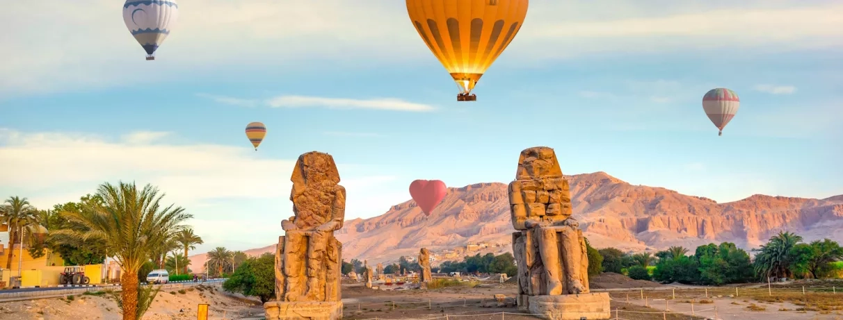 colosses memnon entouré de montgolfiere sous un ciel bleu