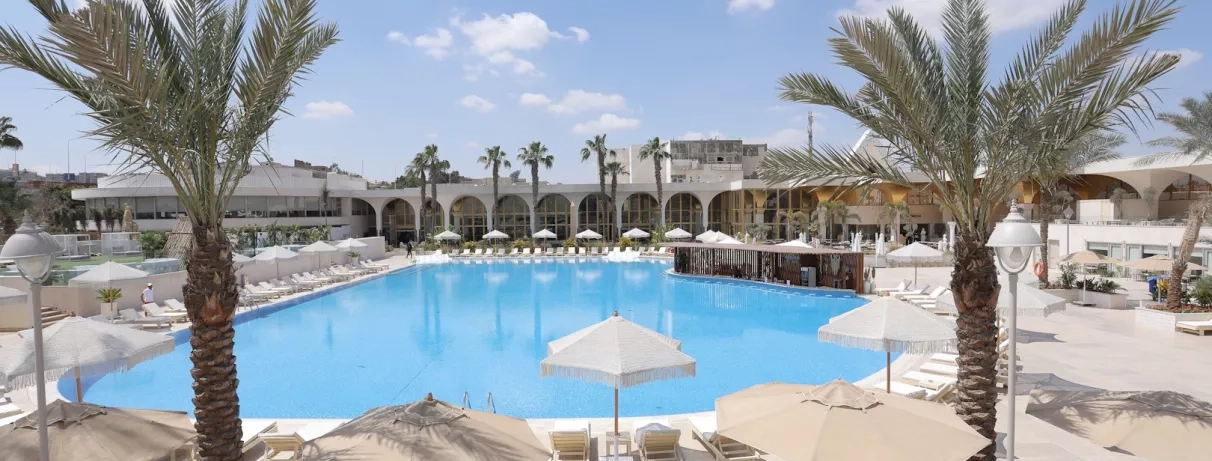 piscine palmiers transats sous un ciel bleu au pyramids park au caire
