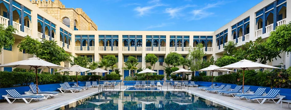 piscine extérieure équipée de transats et bâtiment de l'hôtel