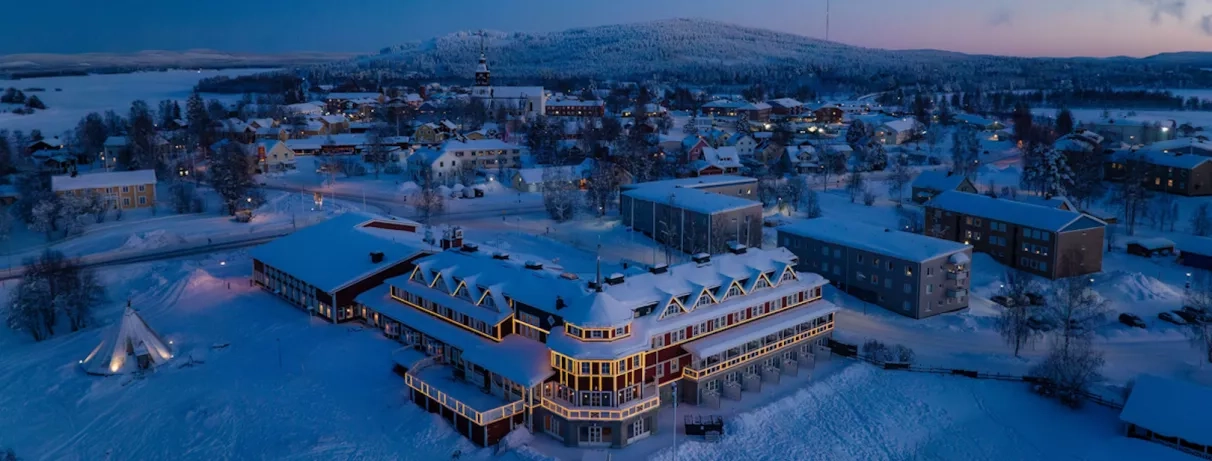 Hôtel Grand Arctic éclairé de nuit au cœur d'un paysage enneigé de Laponie suédoise pour un séjour ou voyage d'hiver.