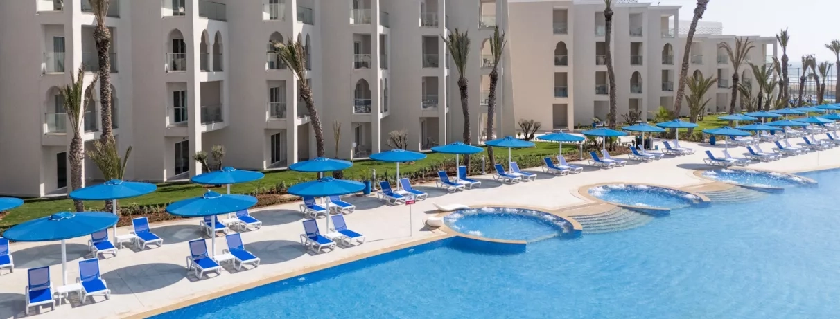 Vue piscine avec immeubles, transats et parasols