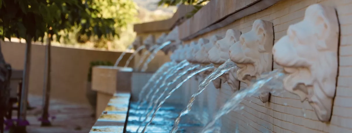 Vue de près d'une fontaine à eau, décoré et sculptés avec des formes de visages.