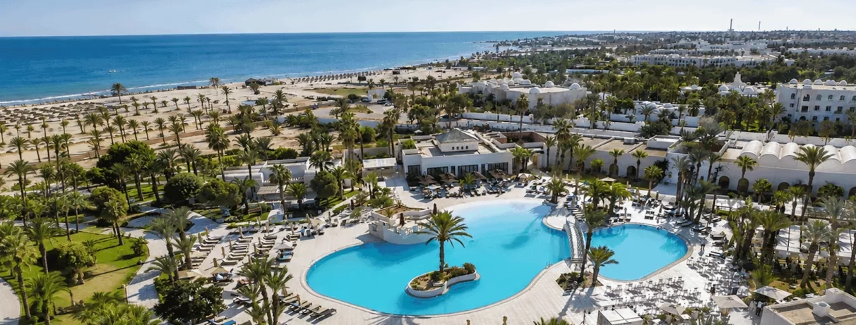 Une vue d'ensemble de l'hôtel, entre piscine à débordement, jardins luxuriants et plage privée, en bordure de mer.