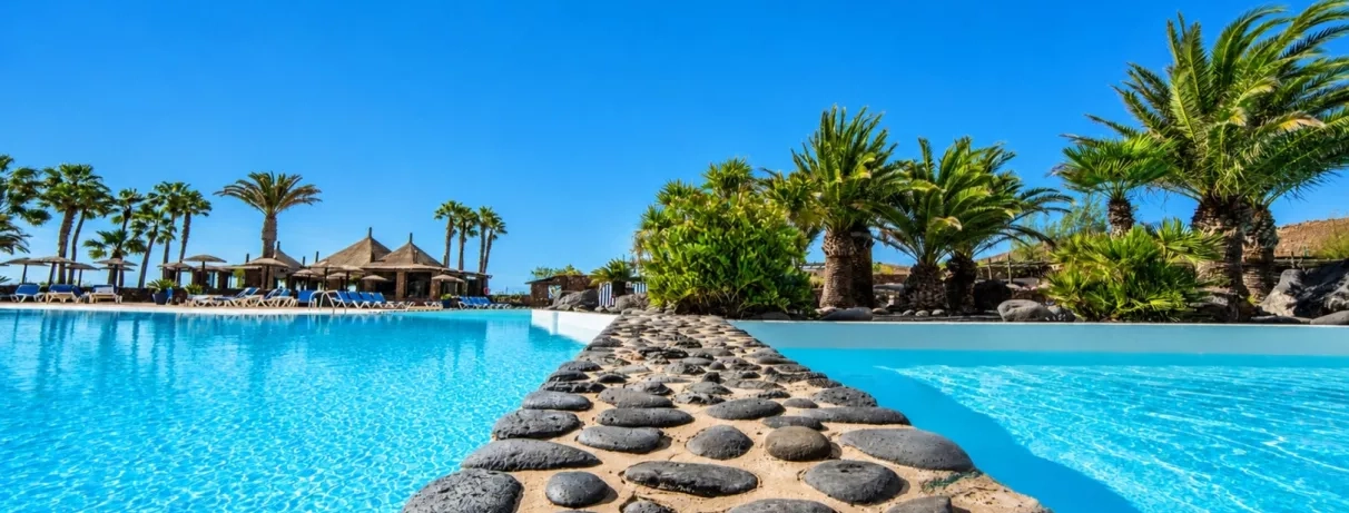 Un gros plan sur une séparation en pierre entre deux sections de la piscine, offrant une vue vers les jardins.