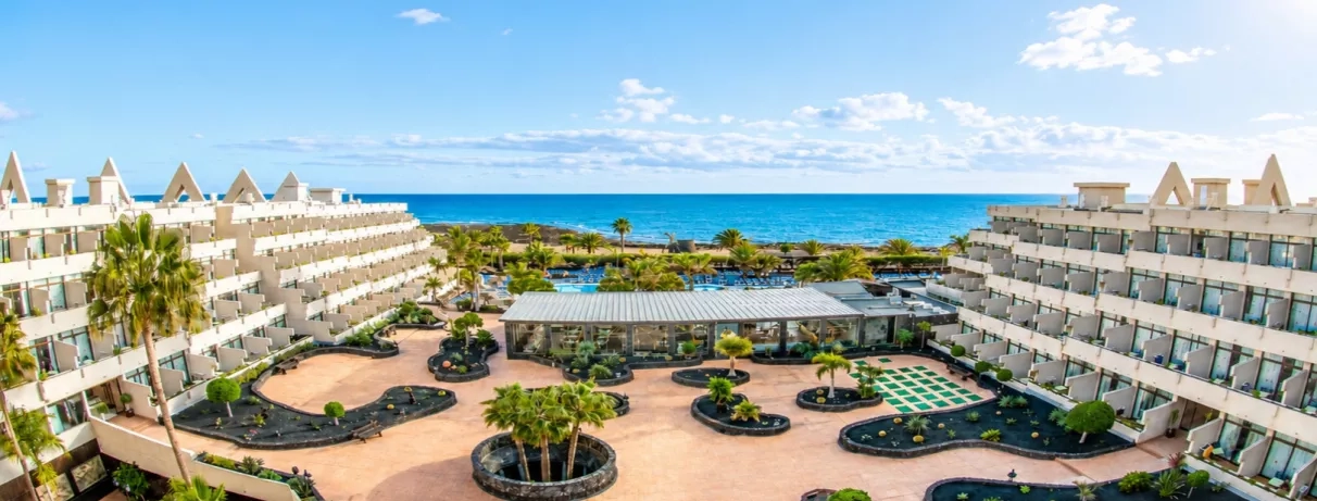Une vue d'ensemble du complexe hôtelier, avec des bassins et des espaces de détente face à la mer.
