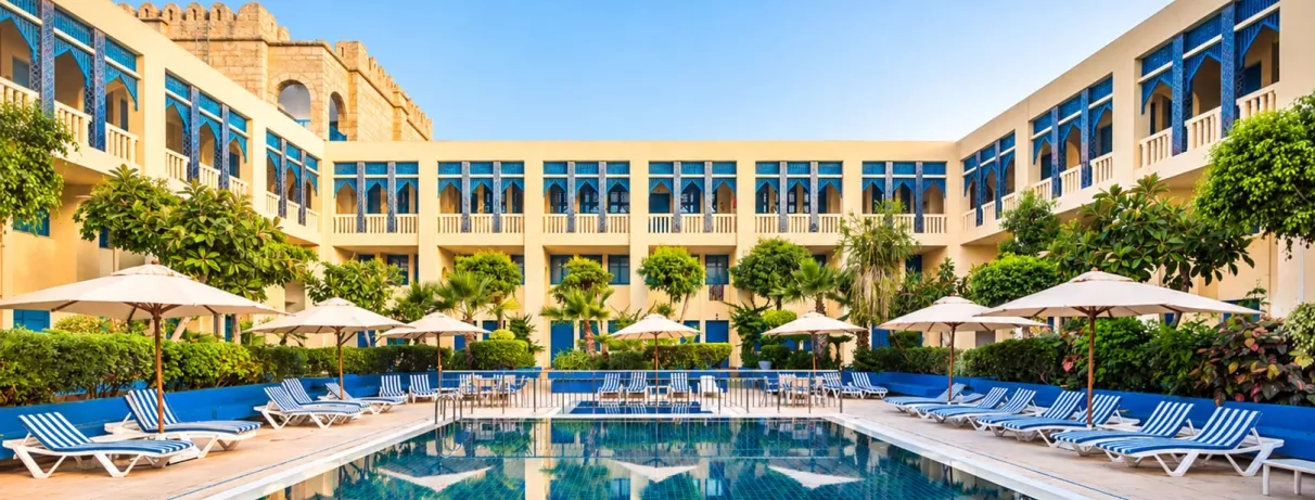 piscine extérieure équipée de transats et bâtiment de l'hôtel