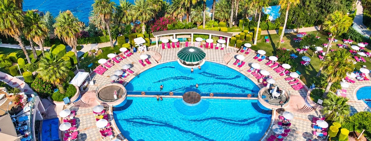 Une vue plongeante sur une grande piscine, entourée de nombreux transats roses.