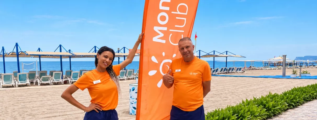 Deux animateurs mondi club sourient sur une terrasse en bord de mer.