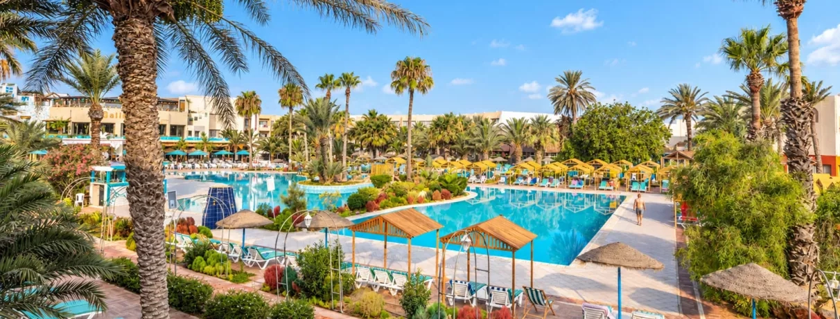 Grande piscine extérieure avec transats et palmiers à l'hôtel tout inclus Welcome Meridiana Djerba