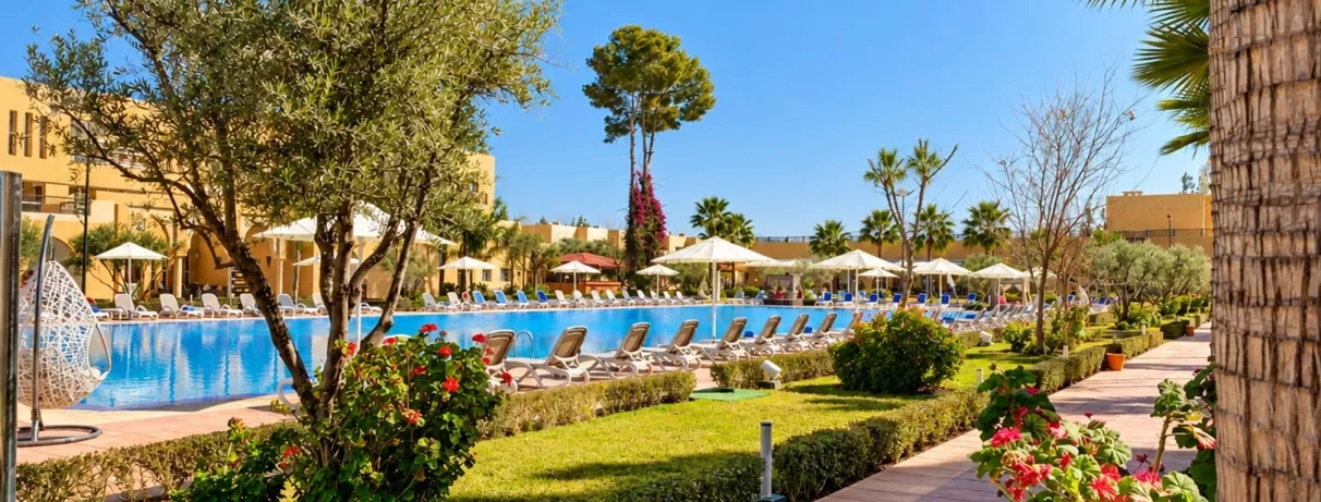 vue générale sur la partie piscine de l'hôtel avec les transats tout autour et une partie jardin