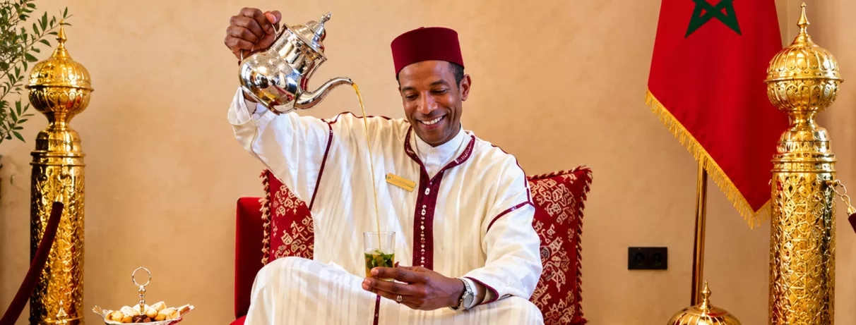 jeune homme en habit traditionnelle servant du thé
