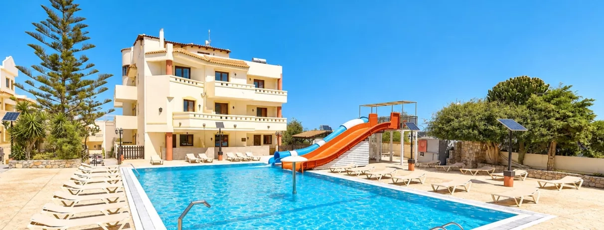 piscine avec transats, deux toboggans, un couvert bleu et blanc, l'autre découvert orange, oliviers, ciel bleu avec quelques nuages