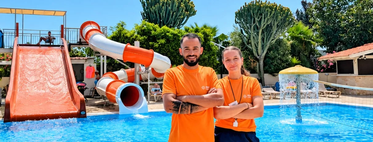 piscine avec transats, deux toboggans, un couvert bleu et blanc, l'autre découvert orange, oliviers, ciel bleu avec quelques nuages