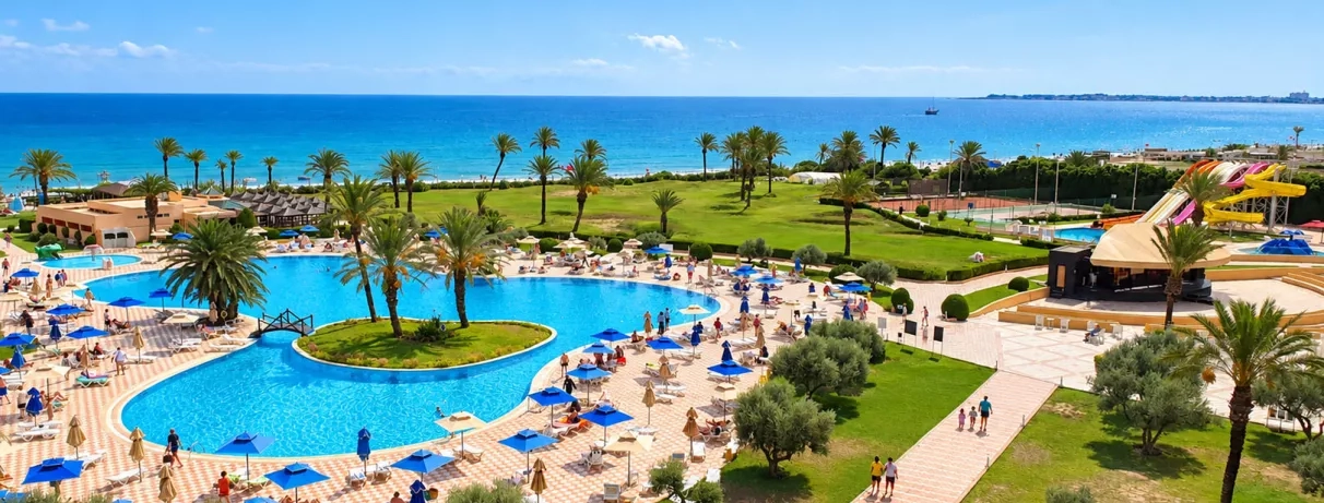 Vue panoramique du complexe Nour Palace Mahdia avec piscine extérieure, toboggans aquatiques et plage en bord de mer.