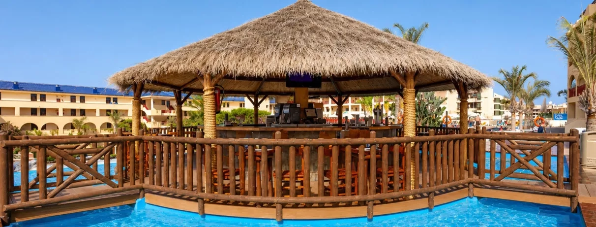 Un bar de piscine avec un toit de chaume, situé au milieu d'une eau turquoise.
