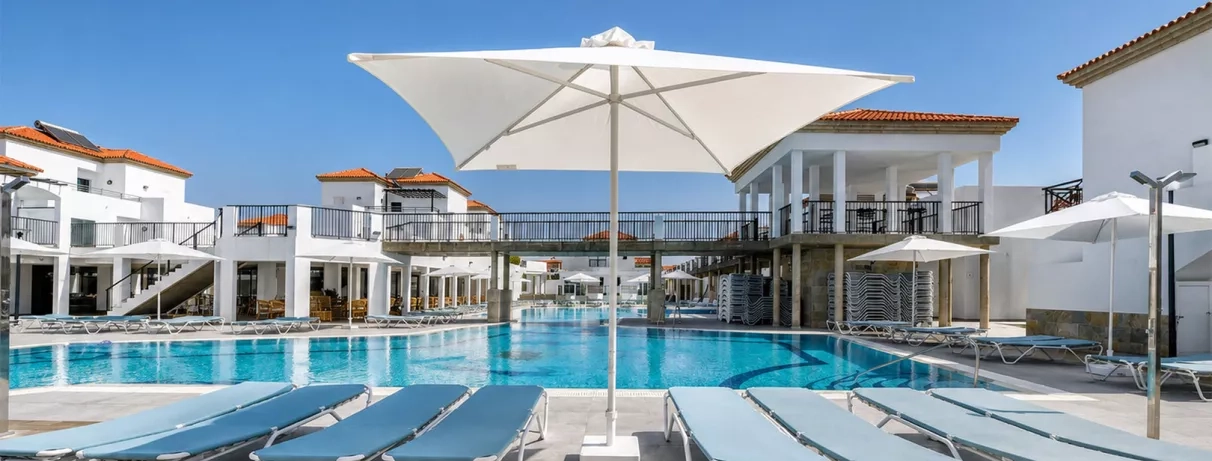 Une vaste piscine ensoleillée bordée de transats confortables et d'un grand parasol blanc.