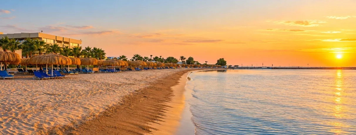 Plage de sable fin et parasols en paillote au Mondi Club Seven Seas Jolie Bay à Hurghada au coucher du soleil.