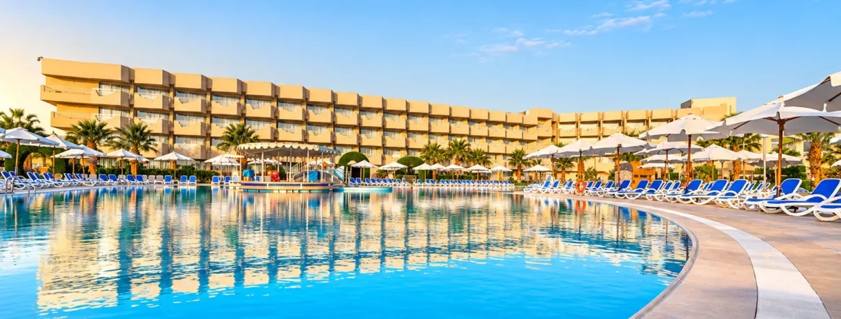 Vue sur la piscine principale et le bâtiment des chambres de l'hôtel Mondi Club Seven Seas Jolie Bay Égypte.