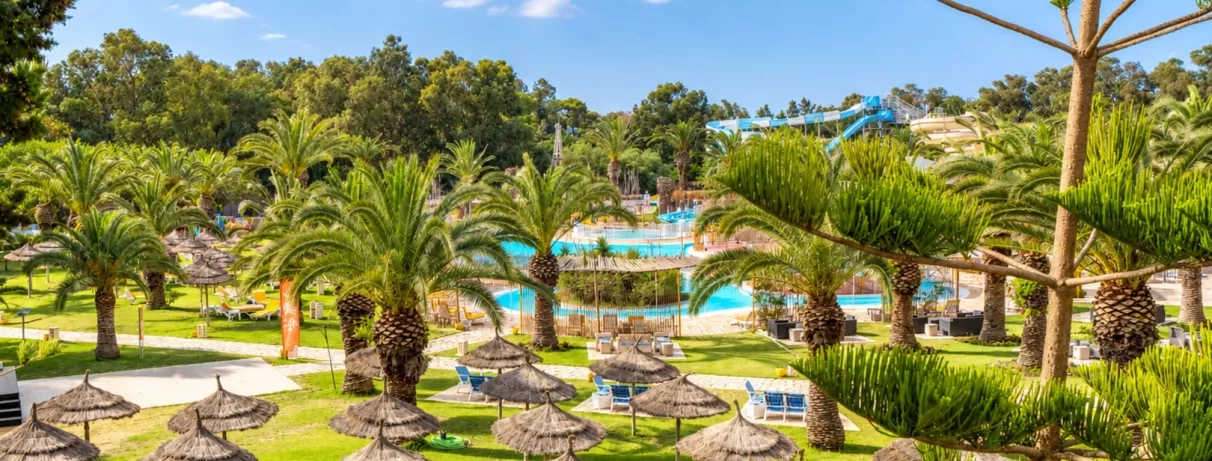 Parc verdoyant et palmeraie de l'hôtel Mondi Club Shalimar à Hammamet avec vue sur le parc aquatique.