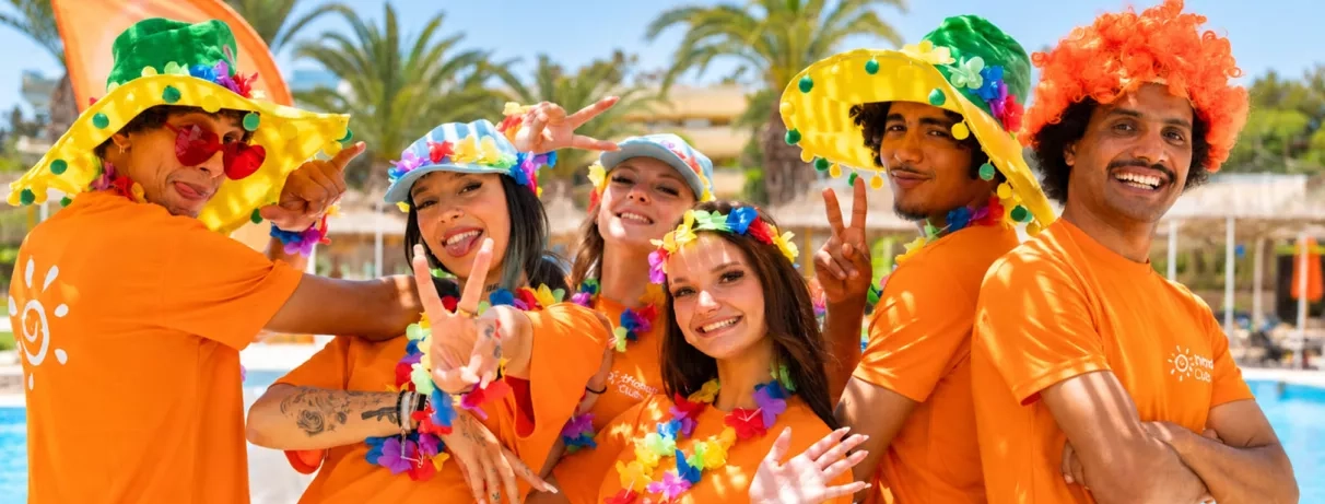 Animateurs souriants du Mondi Club Shalimar Hammamet portant des chapeaux et colliers de fleurs colorés.