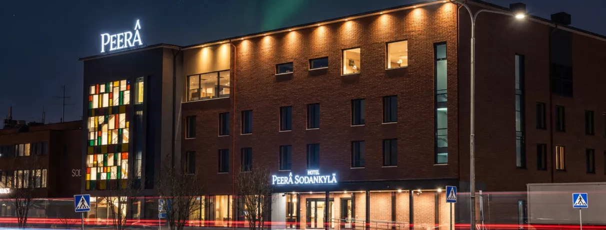 Vue nocturne illuminée du Peerâ Hotel Sodankylä, club de vacances en Laponie.