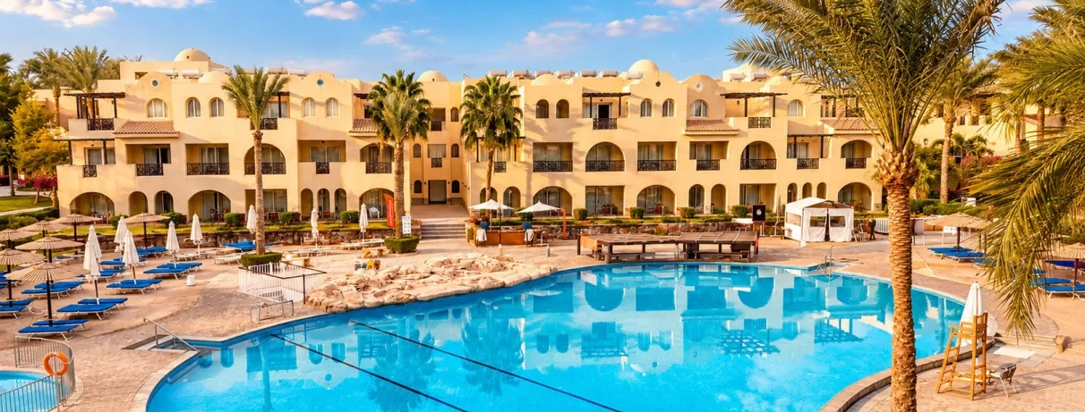 Grande piscine extérieure avec transats devant la façade de l'hôtel Mondi Club Stella Gardens