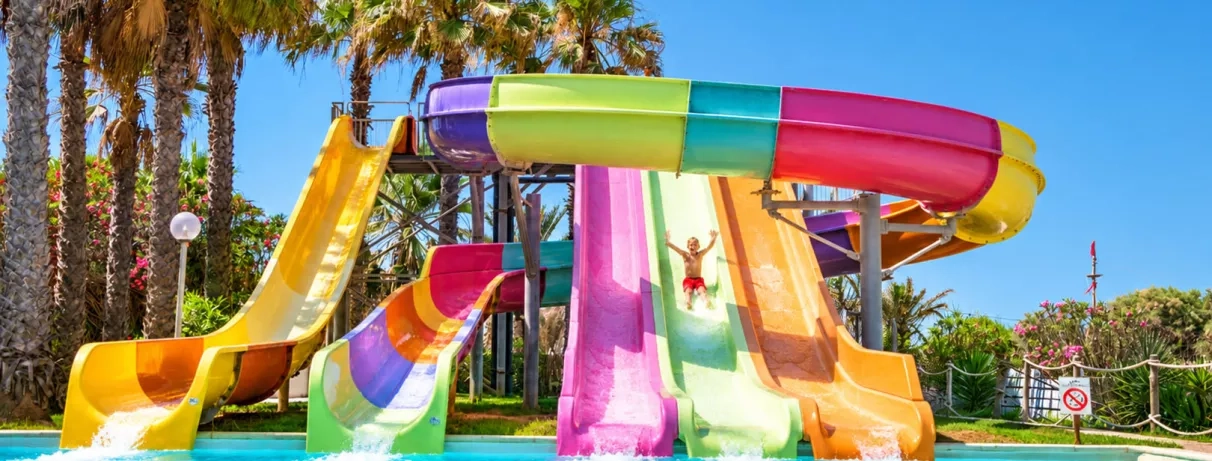 Enfant glissant sur les toboggans colorés de l'aquapark du Mondi Club Thalassa Mahdia pendant un séjour en famille en Tunisie.