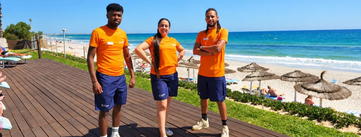 Équipe d'animateurs du Mondi Club Thalassa Mahdia en t-shirts orange posant sur la terrasse face au bord de mer.